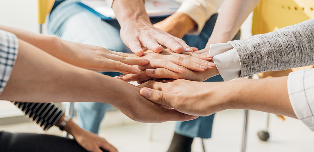 Stock photo of several people touching hands in the middle of a circle