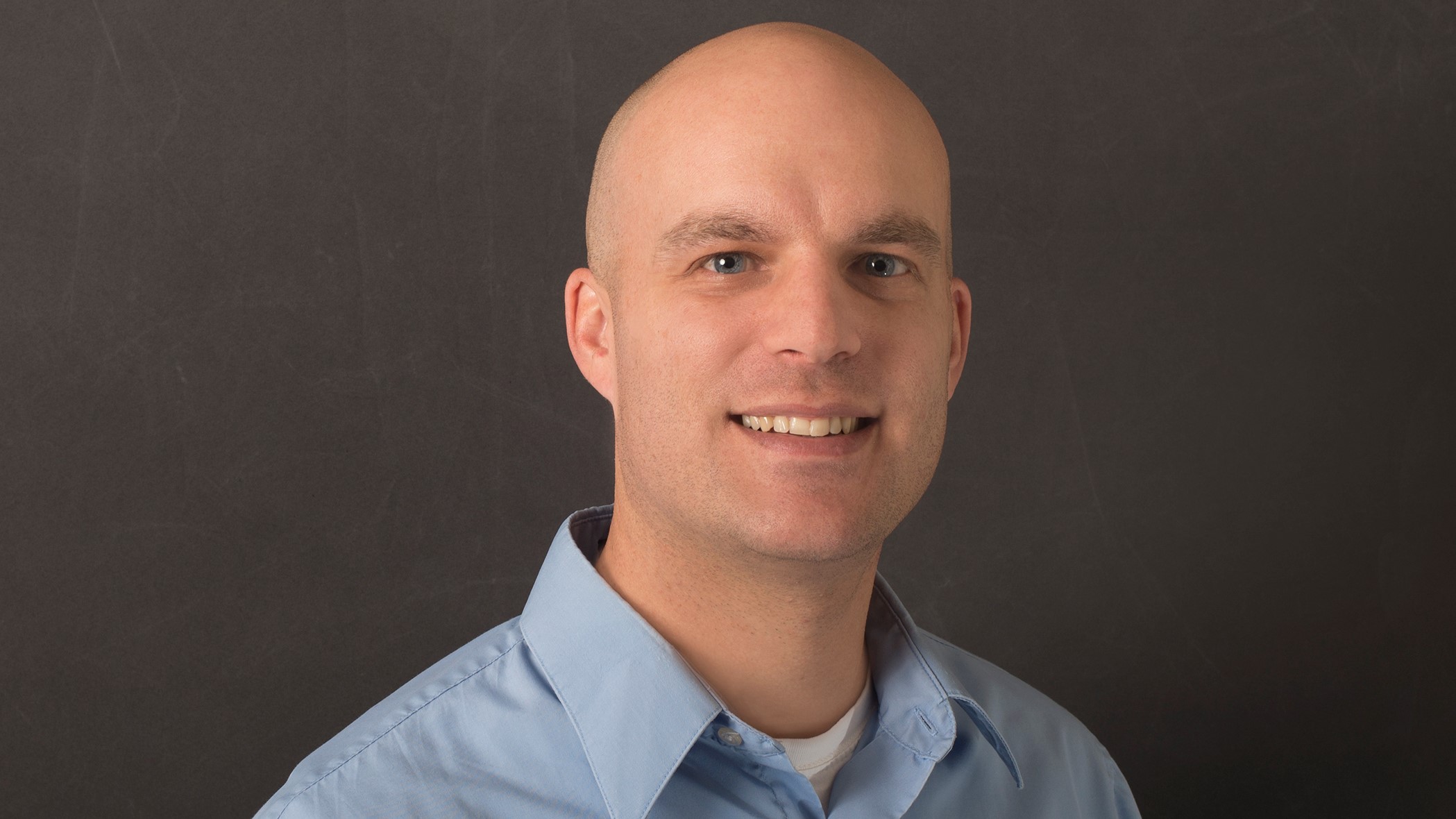 Lucas Vaas, Personal Lines Underwriter, smiles in front of a black background.