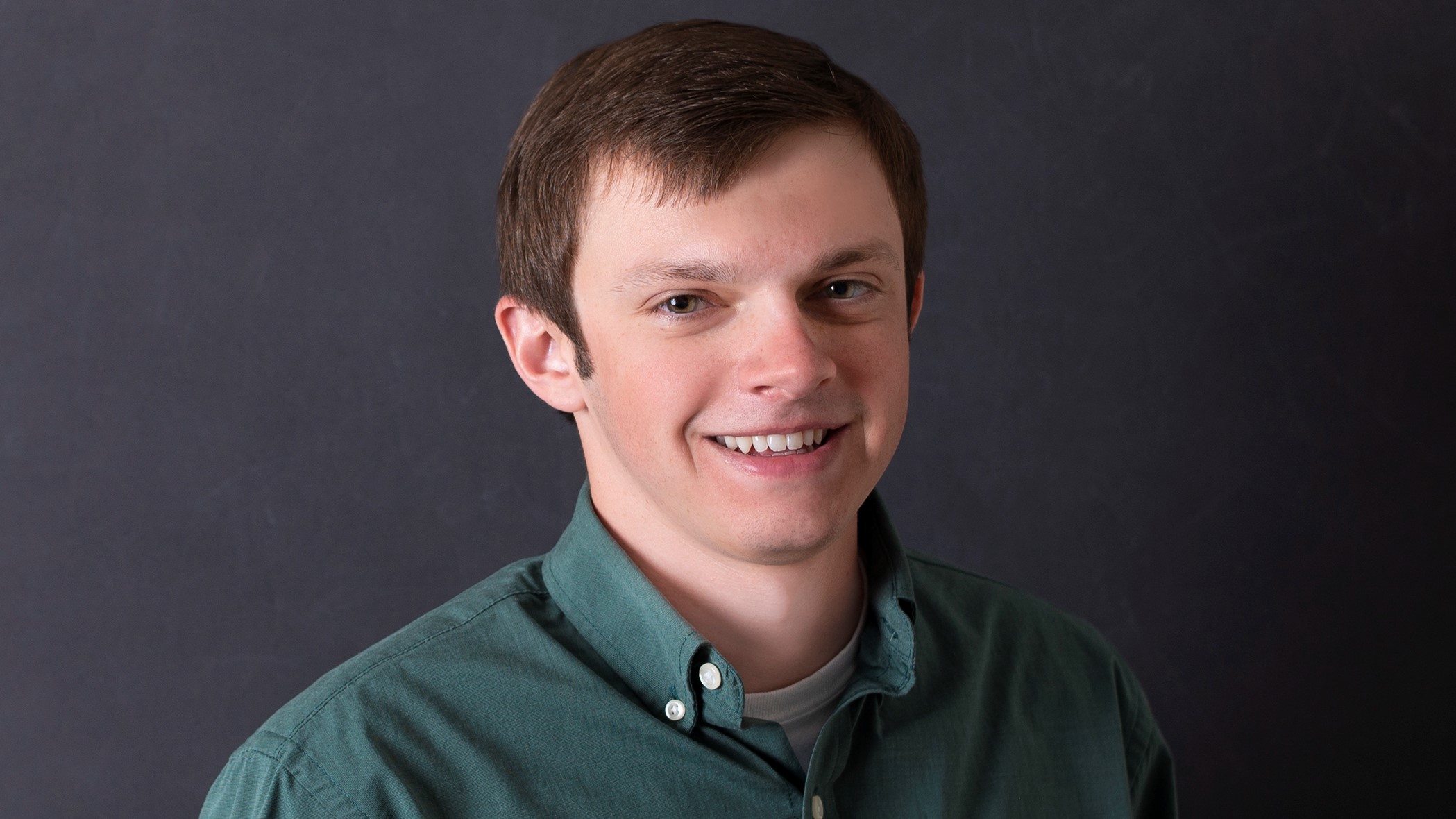 Brayton Adams, Associate Small Business Underwriter at Celina Insurance Group, smiles in front of a black background.