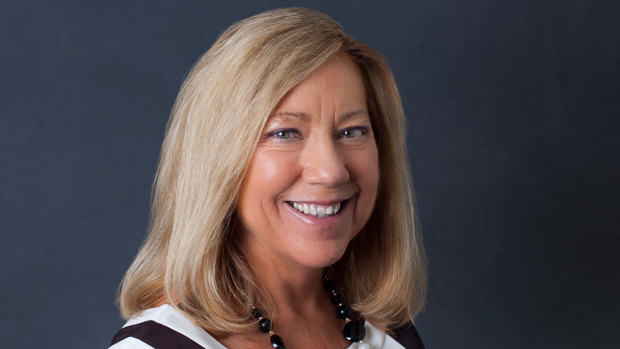 Cathy Bigham, Director of Actuarial and Compliance at Celina Insurance Group, smiles in front of a black backdrop.