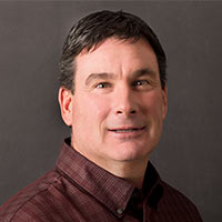 Dick Jones, Indiana Marketing Representative, smiles in front of a black background.