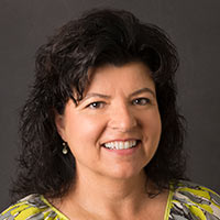 Nina Plant, Tennessee Marketing Representative, smiles in front of a black background.