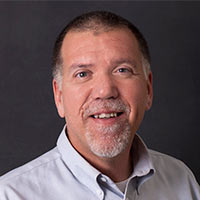 Troy Short, Indiana Marketing Representative, smiles in front of a black background.