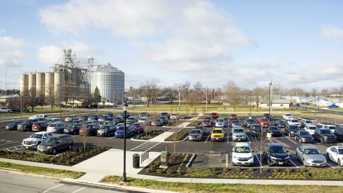 Pictured is the redesigned Celina Insurance Group parking lot. It has trees, pedestrian walkways and is filled with cars.