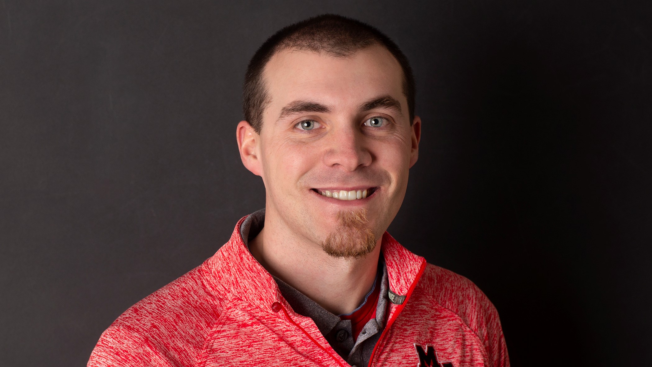 Cayden Cox, Claims Representative at Celina Insurance Group, smiles in front of a black background.