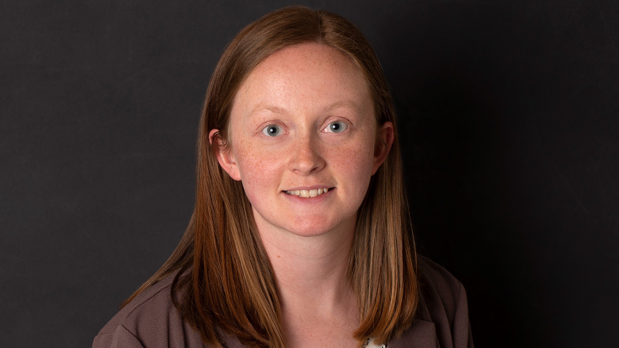 Lexi Noll, Claims Representative Associate at Celina Insurance Group, smiles in front of a black background.