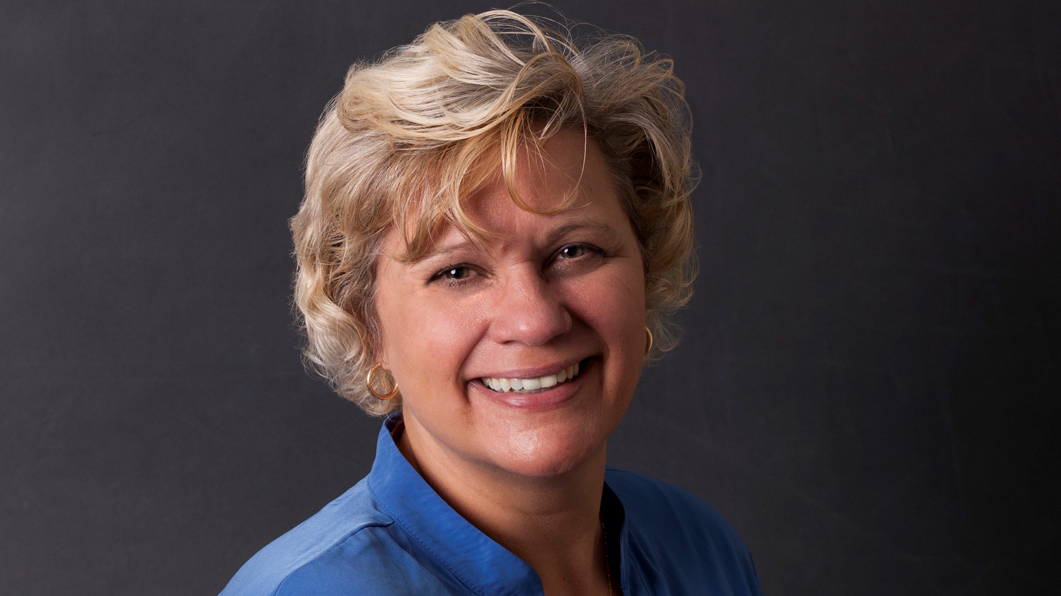 Beth Winner, Senior Premium Audit Specialist at Celina Insurance Group, smiles in front of a black background.