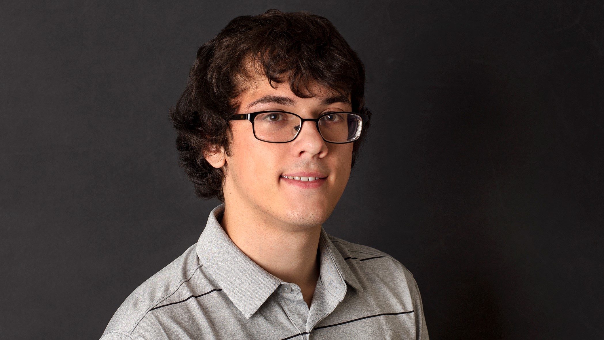 Zachary Lyons, Associate Commercial Lines Services Specialist at Celina Insurance Group, smiles in front of a black background.