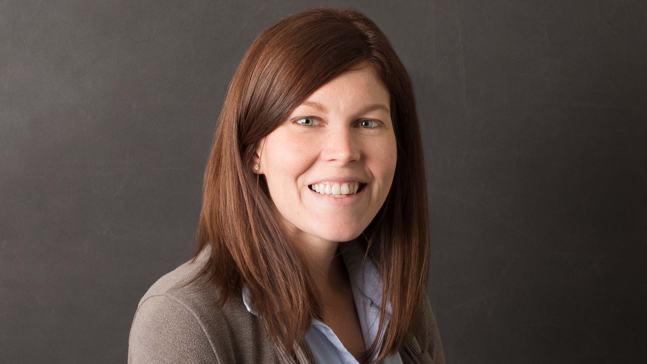 Caitlin Bair, Compliance Supervisor at Celina Insurance Group, smiles in front of a black background.