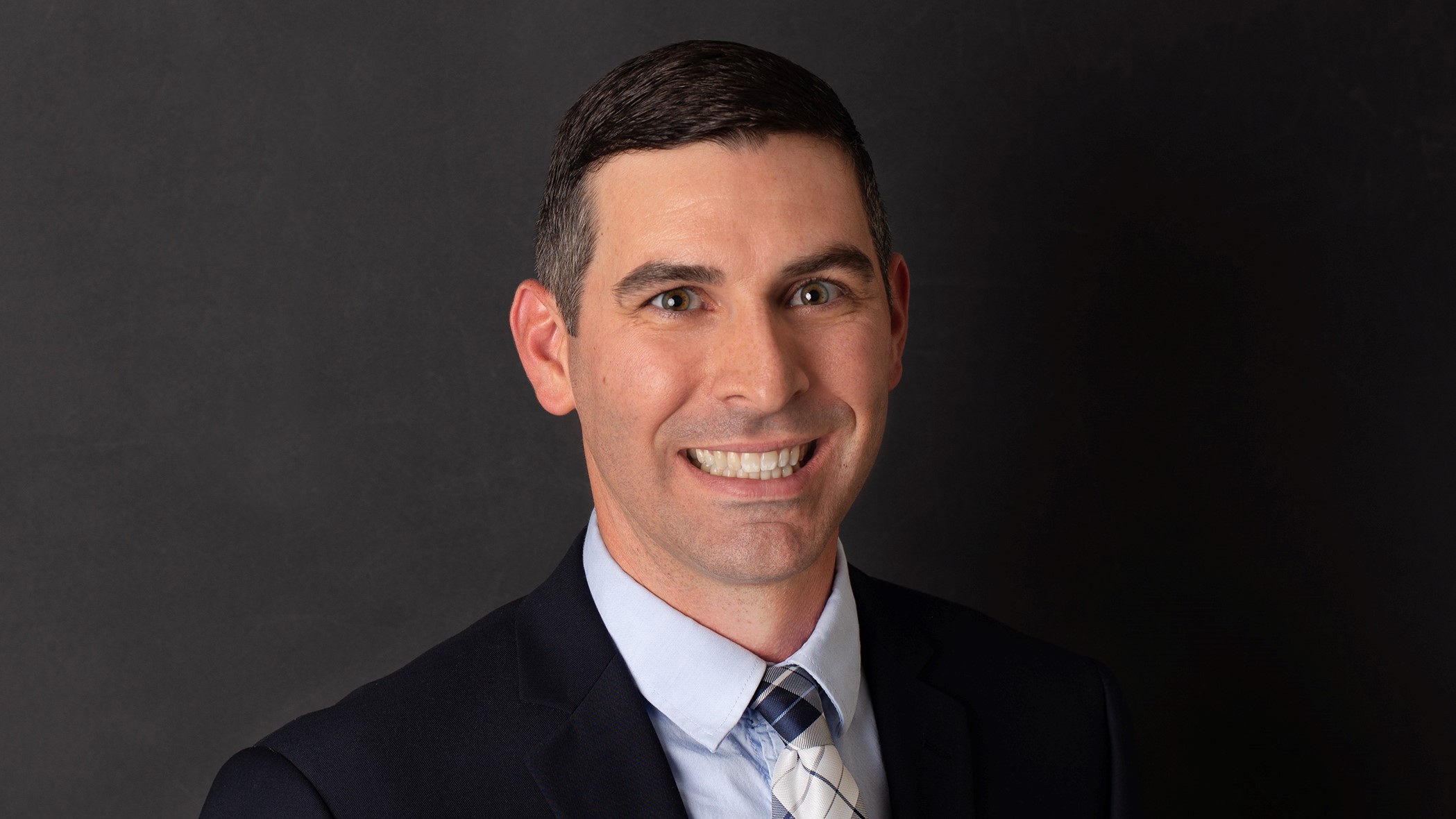 Eric Braun, Celina Insurance Group Internal Auditor, smiles in front of a black background.