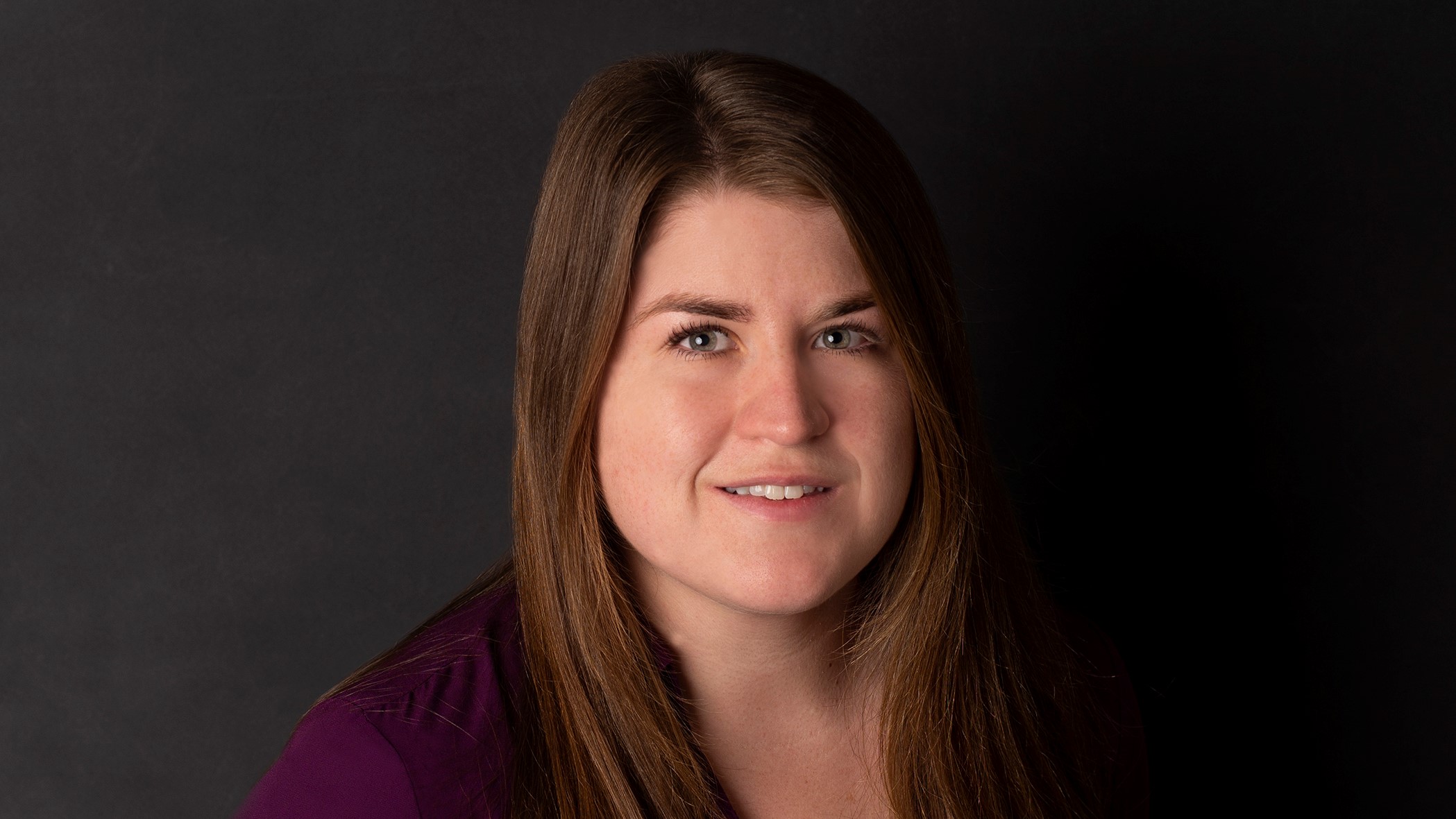 Shannon Osterfeld, Associate Actuary at Celina Insurance Group, smiles in front of a black background.