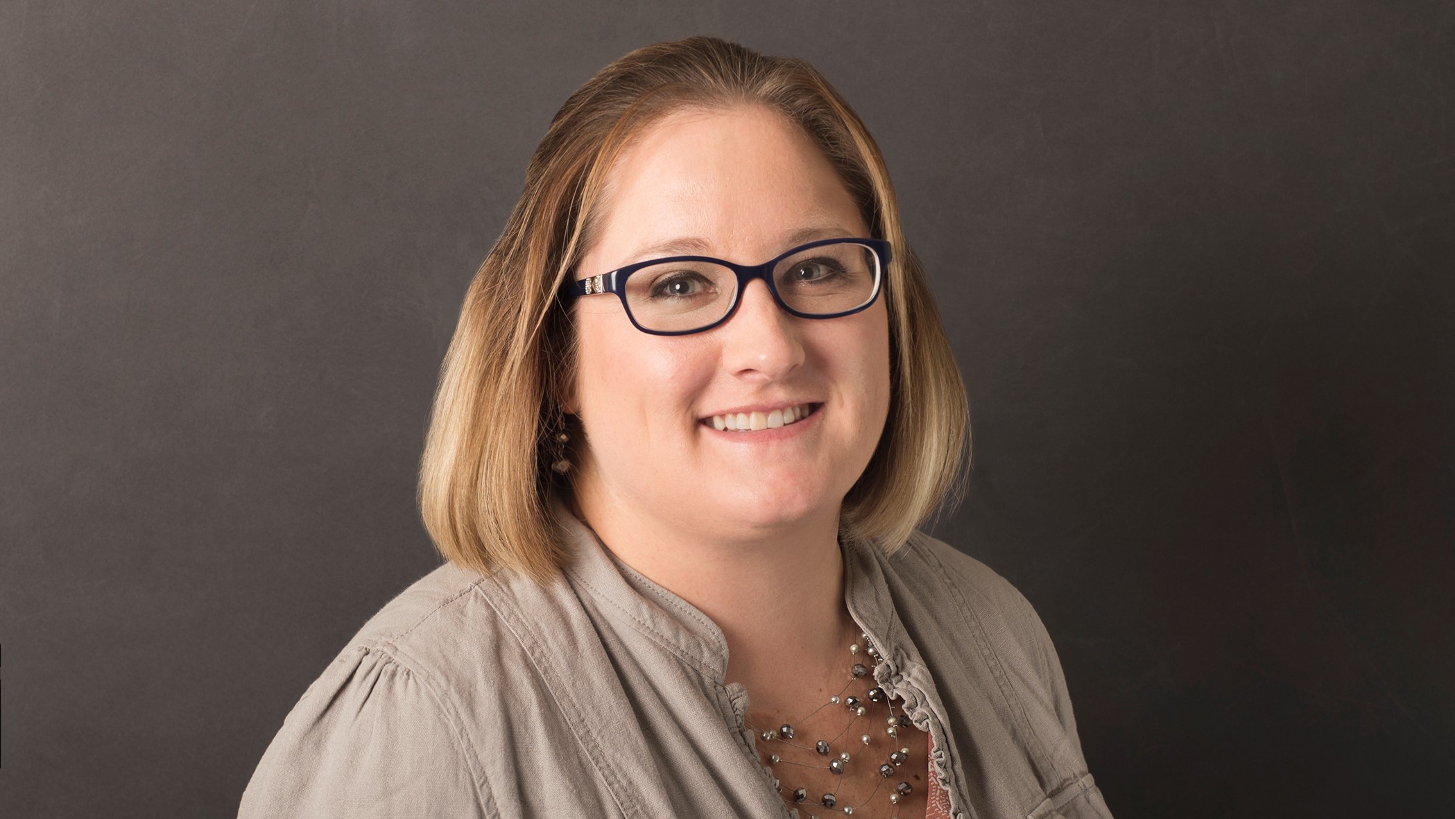 Andrea Buening, Claims Representative at Celina Insurance Group, smiles in front of a black background