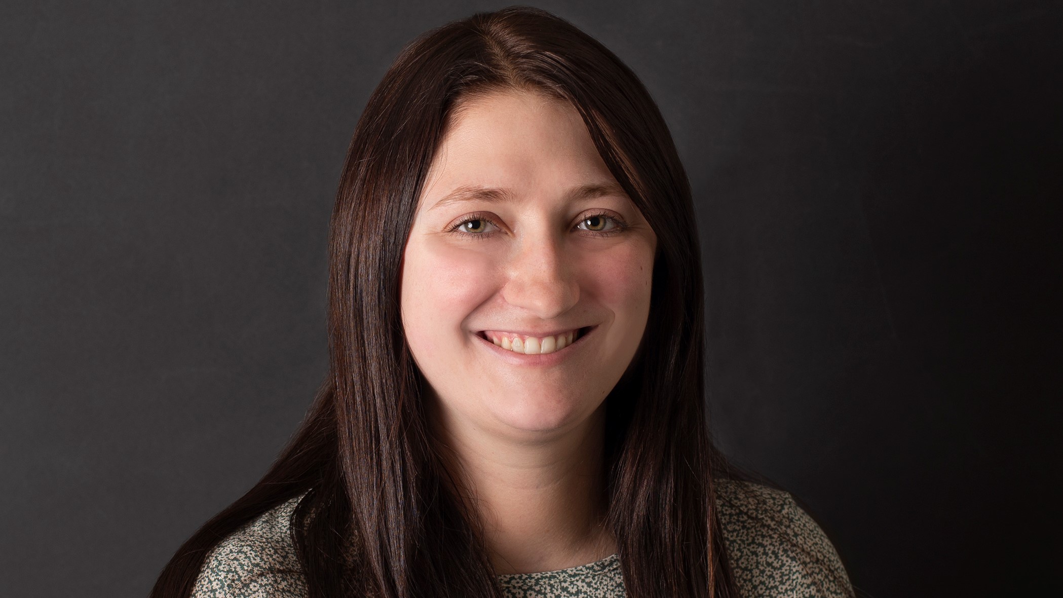 Devin Post, Associate Small Business Underwriter at Celina Insurance Group, smiles in front of a black background.