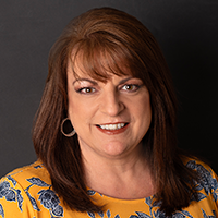 Jenny Cantrell, West Virginia Marketing Representative, smiles in front of a black background.