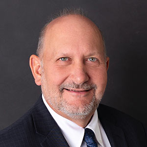 Rob Shoenfelt, Sr. Vice President – Chief Information and Innovation Officer, smiles in front of a black background.