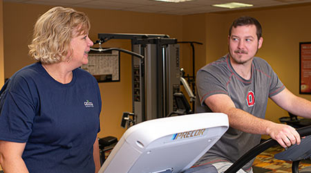 Two employees have a conversation while exercising in a company fitness center.