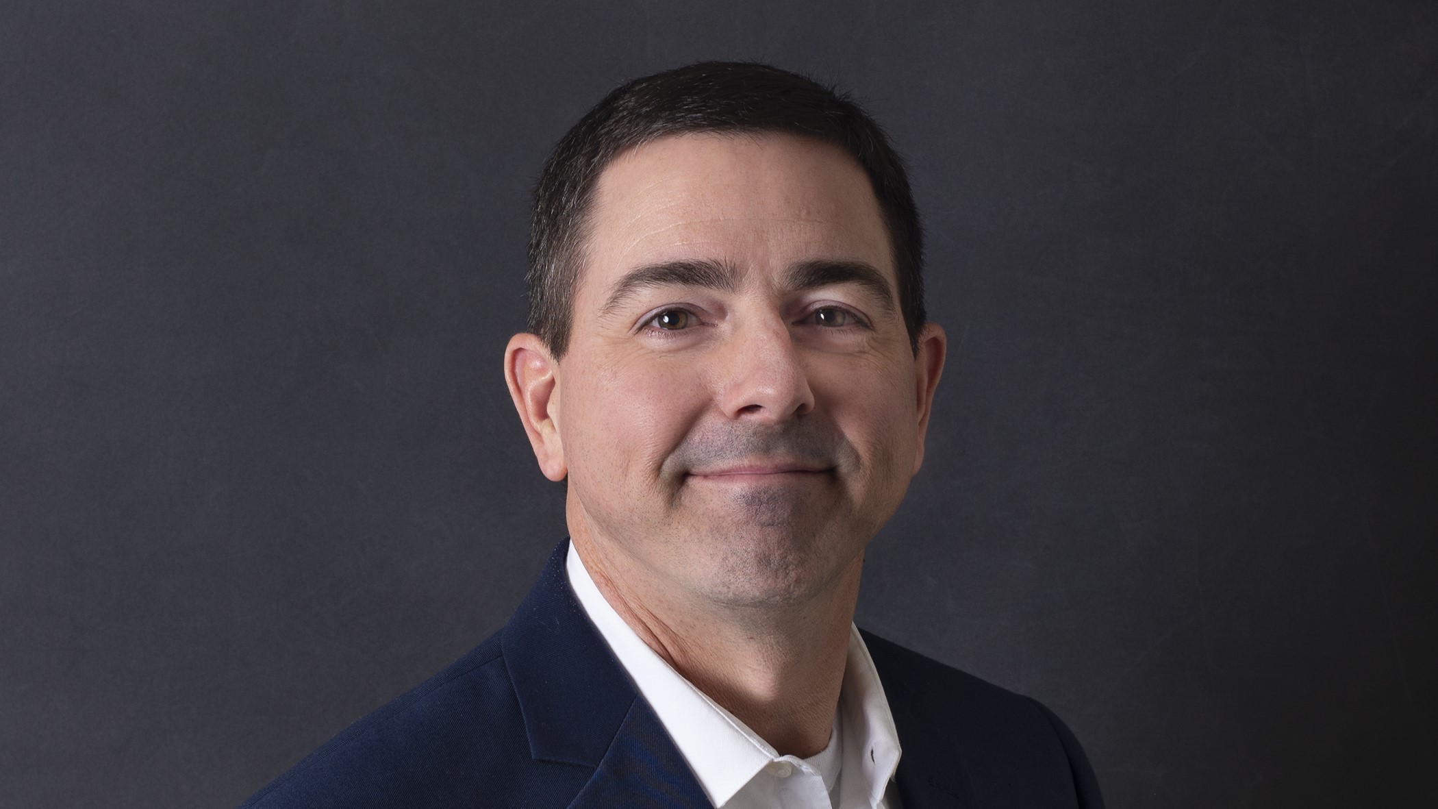 Rob Howell, Innovation and Customer Experience Manager at Celina Insurance Group, smiles in front of a black background.