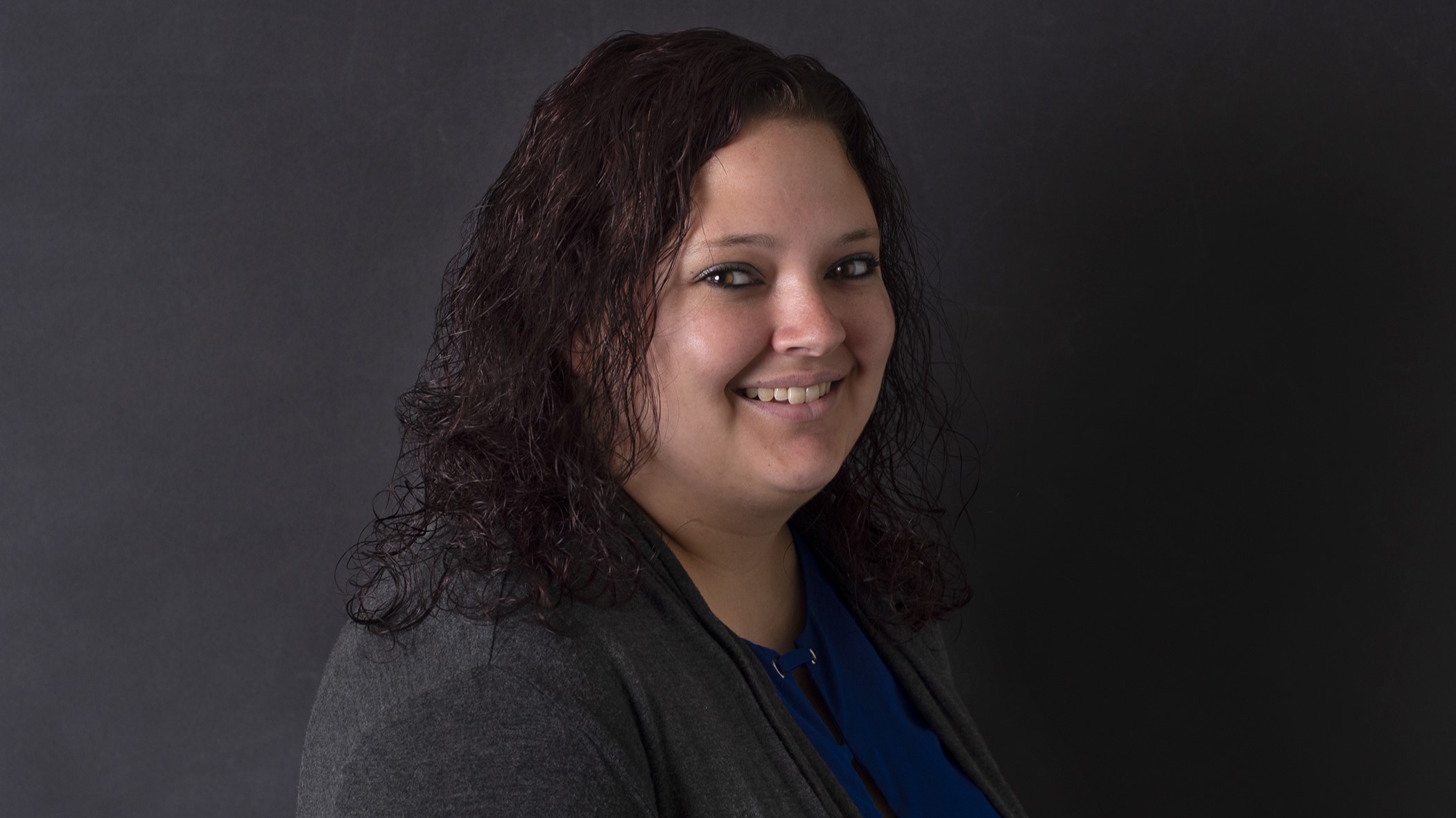 Janelle Luebke, Senior Small Business Underwriter at Celina Insurance Group, smiles in front of a black background.